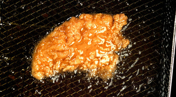 Breaded chicken frying in oil at a restaurant fryer