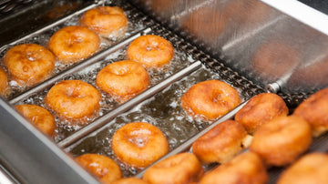 donuts sitting in frying oil cooking hot and nice brown glazed frying oil fried donut