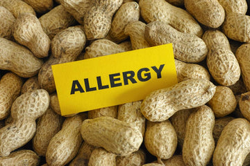 peanuts in a massive pile with a sign that says "allergy" on it to warn about peanut allergy risk in frying peanut oil