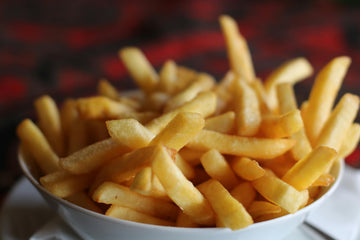 Commercial deep fryer with golden-brown french fries being lifted from oil