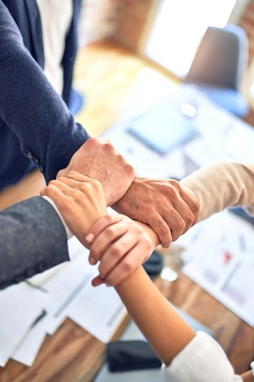 staff coming together at a corporate desk and joining arms