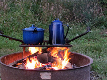 Cooking at a higher altitude with pots and pans over a fire in the mountains during dusk
